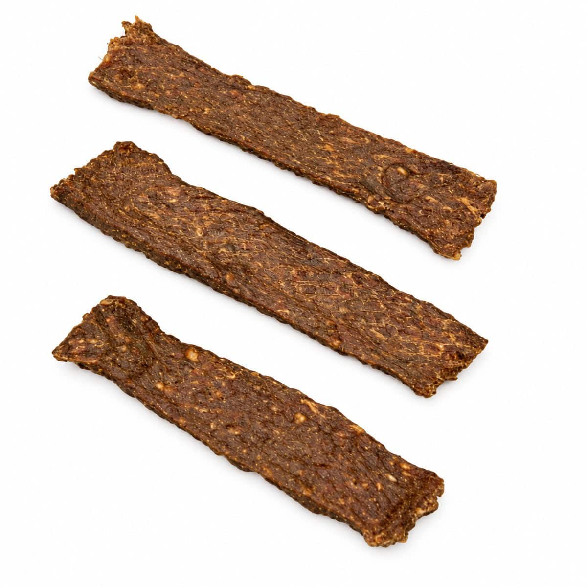 Gedroogde geitenvleesstrips op een witte achtergrond.